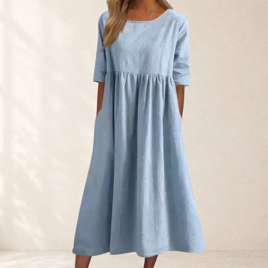 Elegant Cindy dress from THE WHITMORE FAMILY displayed on a hanger with intricate detailing and flowing fabric.