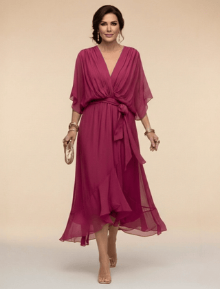 Mona V-neck dress by THE WHITMORE FAMILY displayed on a hanger, featuring a stylish V-neckline and flowing fabric.