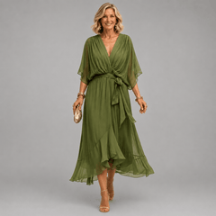 Mona V-neck dress by THE WHITMORE FAMILY displayed on a hanger, featuring a flowing fabric and elegant V-neck design.
