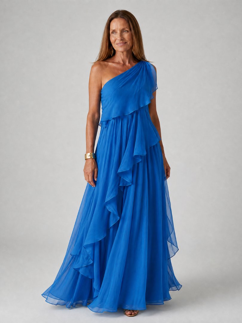 Talia cascading ruffle maxi dress by THE WHITMORE FAMILY, flowing fabric with layered ruffles, worn by a model in a sunny outdoor setting.