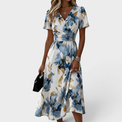 Floral wrap midi dress by THE WHITMORE FAMILY featuring a waist tie and a vibrant floral pattern, showcased on a model.