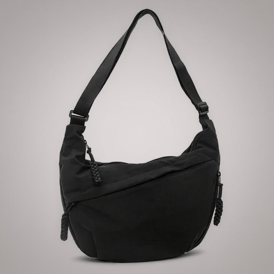 Black Aria crossbody bag by THE WHITMORE FAMILY, featuring sleek design and adjustable strap, shown on a neutral background.