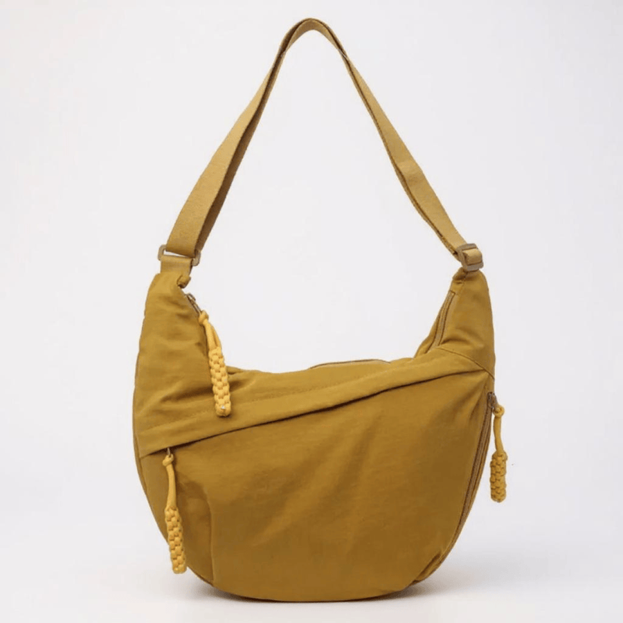 Luce mustard crossbody bag by THE WHITMORE FAMILY with adjustable strap and minimalist design, displayed on a neutral background.