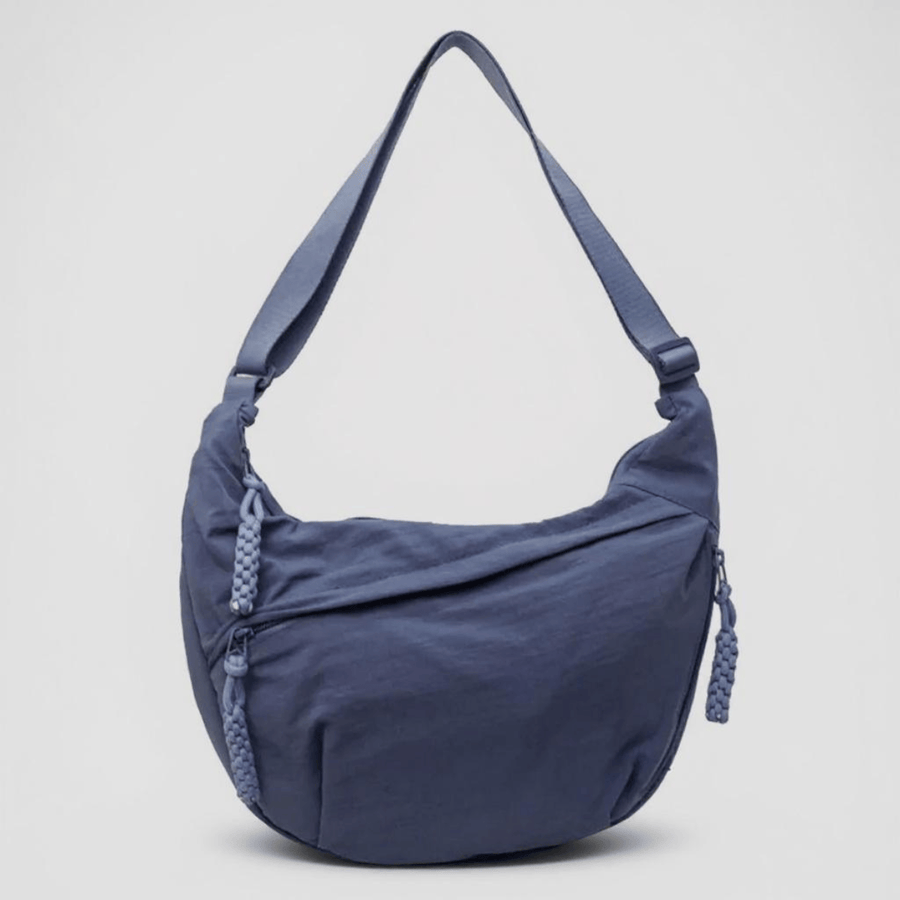 Blue Mara crossbody bag by THE WHITMORE FAMILY with adjustable strap and sleek design, perfect for casual or chic outfits.