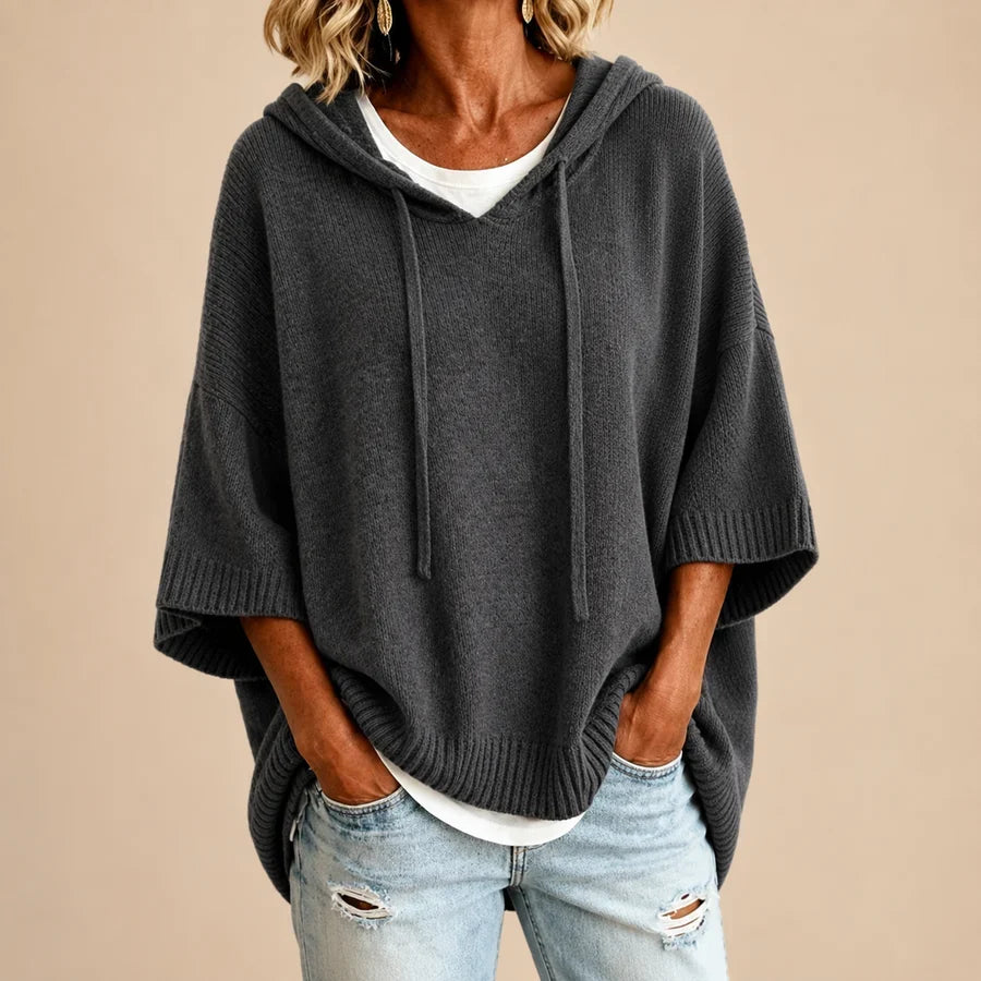 Gray knitted hooded poncho from THE WHITMORE FAMILY, featuring cozy, textured knit fabric and a relaxed, stylish fit.