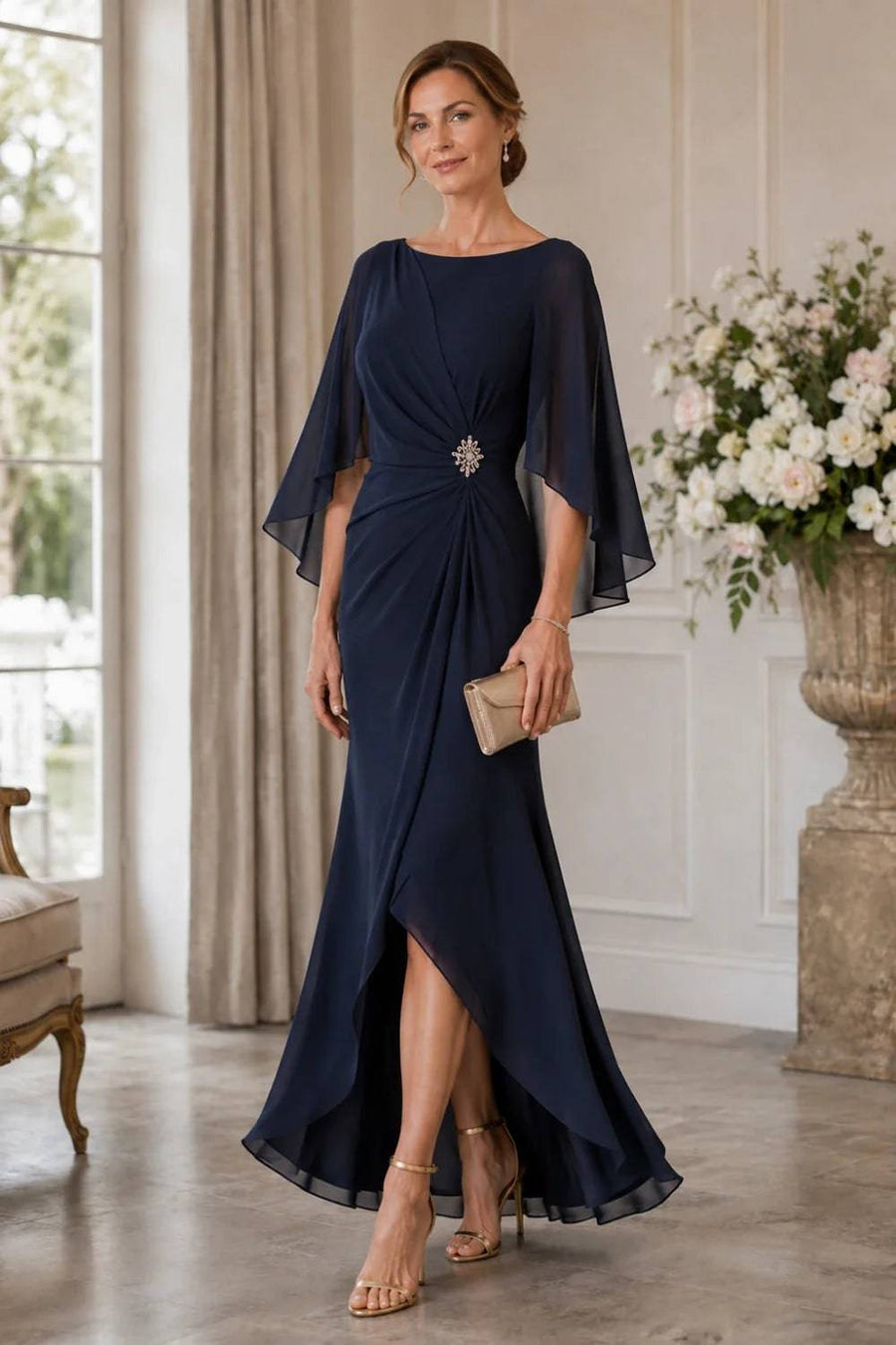 Navy chiffon cape sleeve wrap formal dress by THE WHITMORE FAMILY with a decorative brooch, shown on a mannequin.