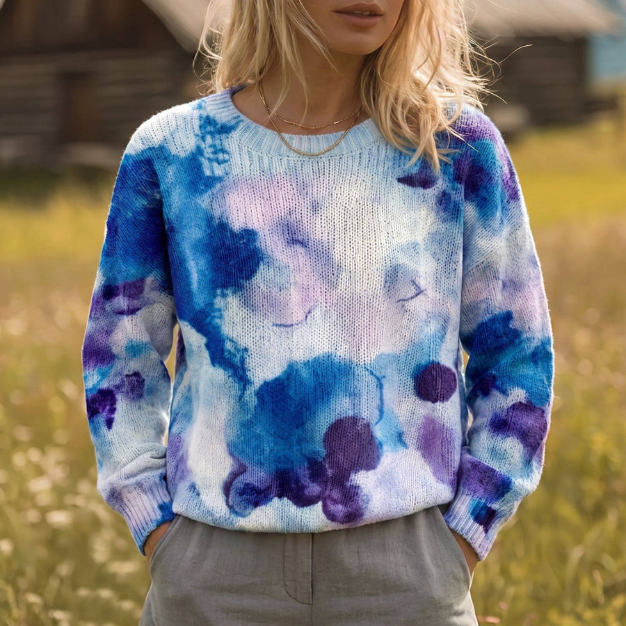 The Anya tie-dye sweater by THE WHITMORE FAMILY featuring vibrant colors and a cozy, casual fit displayed on a hanger.