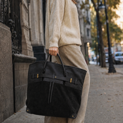 The Juliette Suede Tote bag by THE WHITMORE FAMILY, styled in a casual setting, showcasing its spacious design and soft suede material.