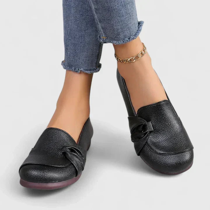 Black Ivarynn elegant shoes by THE WHITMORE FAMILY, featuring a sleek design with pointed toes and stylish detailing.