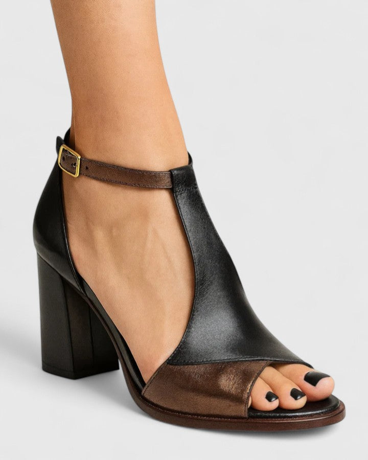 Black Kenzira modern heels by THE WHITMORE FAMILY featuring sleek design and pointed toes on a white background.