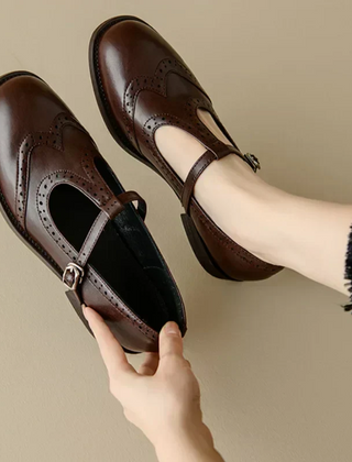 Black Patricia T-strap Mary Janes by THE WHITMORE FAMILY featuring a sleek, elegant design with a rounded toe and comfortable fit.