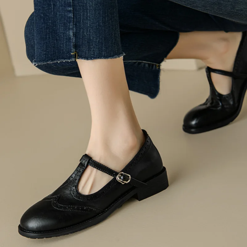 Black Patricia T-strap Mary Janes by THE WHITMORE FAMILY featuring a sleek design and elegant straps, perfect for stylish footwear.