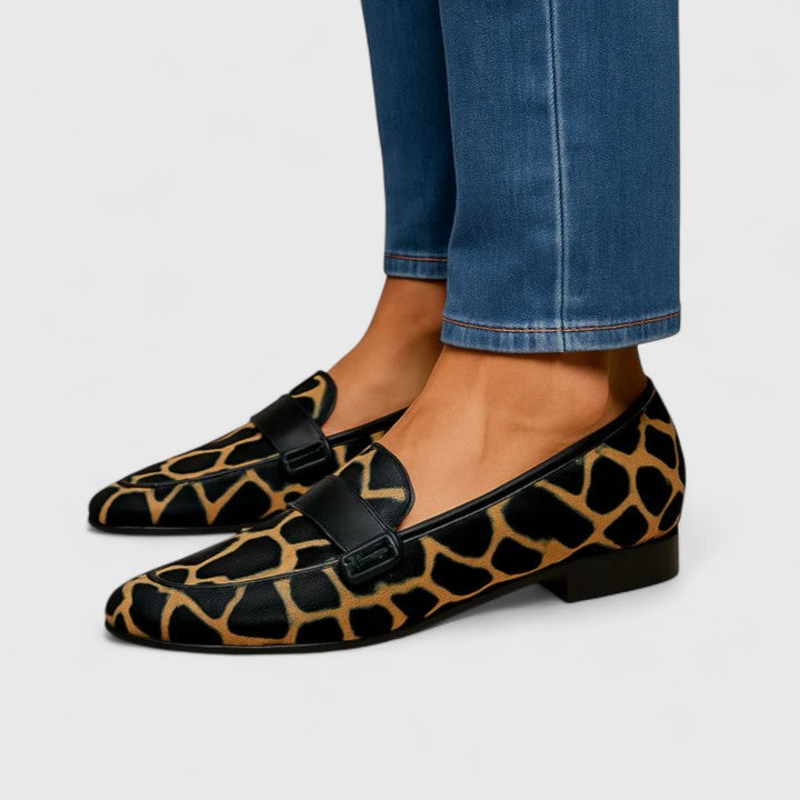 Black and gold Kleirra Timeless Loafers by THE WHITMORE FAMILY, showcasing sleek leather design and classic style.