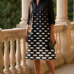 Black Faye Evening Walk Dress by THE WHITMORE FAMILY displayed on a hanger, showcasing its elegant, flowing fabric and classic style.