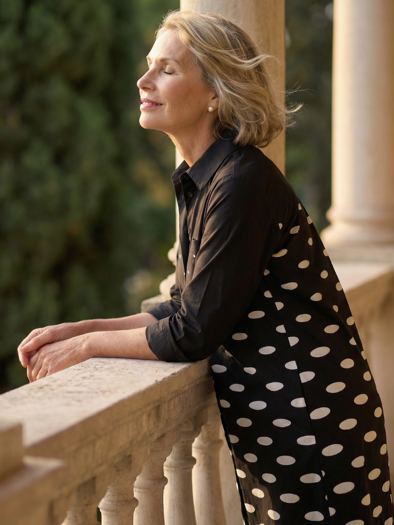 Black Faye Evening Walk Dress by THE WHITMORE FAMILY displayed on a hanger, showcasing its elegant design and fabric texture.