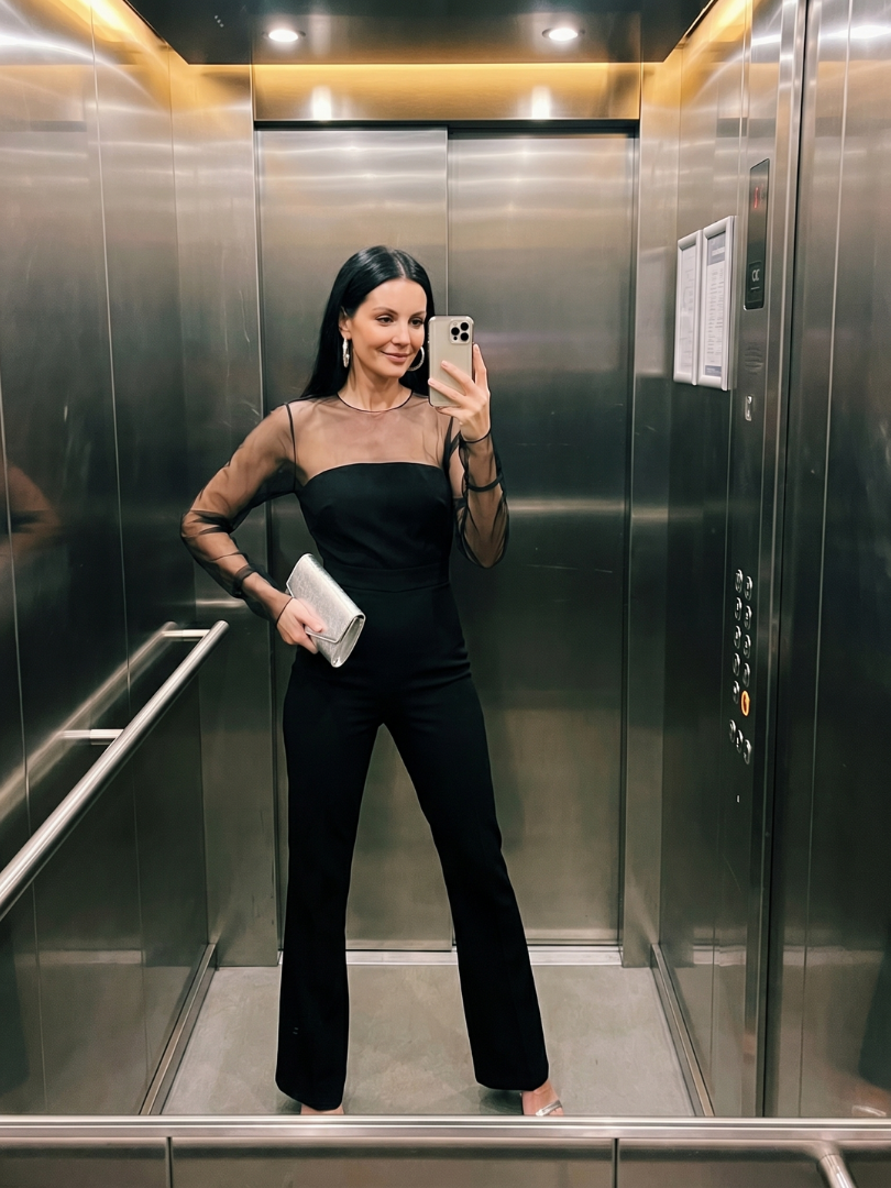Black Oksana sheer fitted bodice flared leg jumpsuit by THE WHITMORE FAMILY, showing a close-up of the stylish design and fabric details.