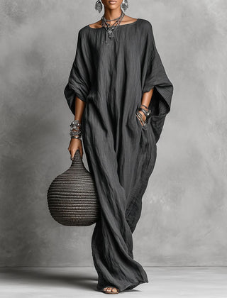 Black Serena oversized maxi dress by THE WHITMORE FAMILY, flowing fabric and relaxed fit, displayed hanging.