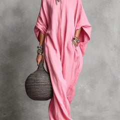 Black Serena oversized maxi dress by THE WHITMORE FAMILY hanging on a wooden hanger with flowing fabric and a relaxed fit.