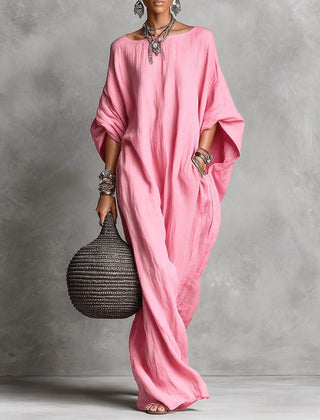 Black Serena oversized maxi dress by THE WHITMORE FAMILY hanging on a wooden hanger with flowing fabric and a relaxed fit.