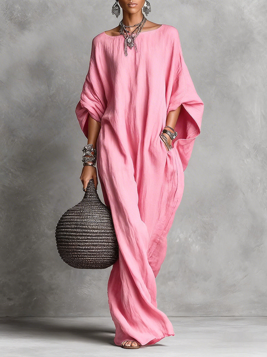 Black Serena oversized maxi dress by THE WHITMORE FAMILY hanging on a wooden hanger with flowing fabric and a relaxed fit.