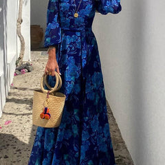 Blue Francesca long floral print dress by THE WHITMORE FAMILY, featuring a flowing silhouette and vibrant floral pattern.