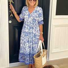 Blue Keisha floral V-neck dress by THE WHITMORE FAMILY, featuring a graceful design and vibrant floral pattern.