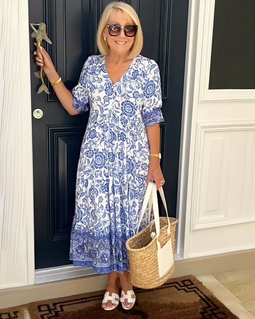 Blue Keisha floral V-neck dress by THE WHITMORE FAMILY, featuring a graceful design and vibrant floral pattern.