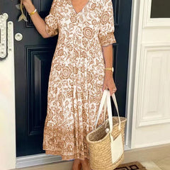 Blue Keisha floral V-neck dress by THE WHITMORE FAMILY, featuring a graceful design with vibrant floral patterns.
