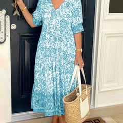 Blue Keisha floral V-neck dress by THE WHITMORE FAMILY, featuring a graceful design and vibrant floral pattern.