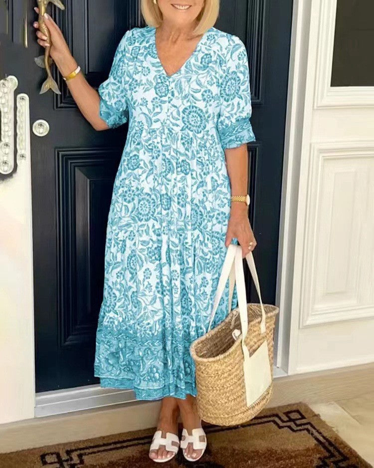 Blue Keisha floral V-neck dress by THE WHITMORE FAMILY, featuring a graceful design and vibrant floral pattern.