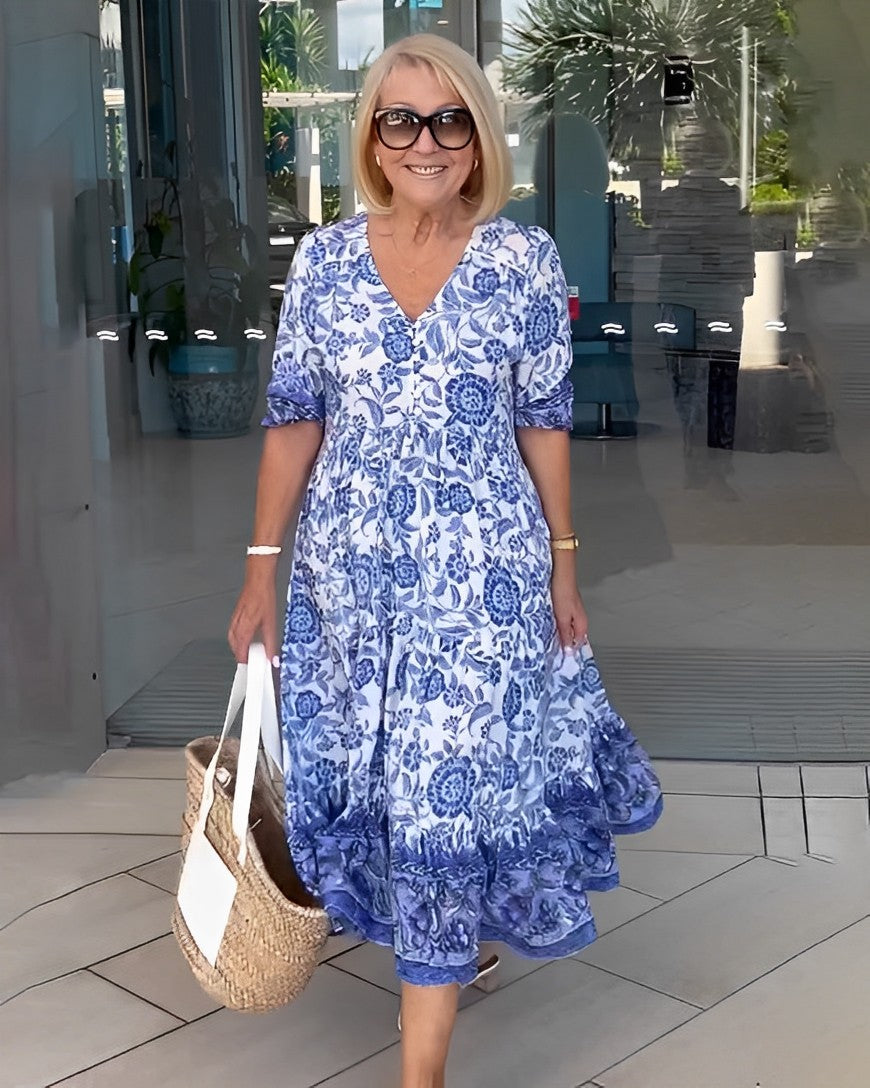 Blue Keisha floral V-neck dress by THE WHITMORE FAMILY, featuring a graceful design and vibrant floral pattern.