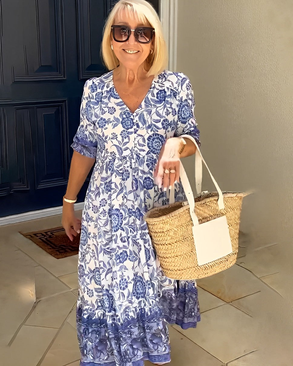 Blue Keisha floral V-neck dress by THE WHITMORE FAMILY, featuring a graceful design with vibrant floral patterns.