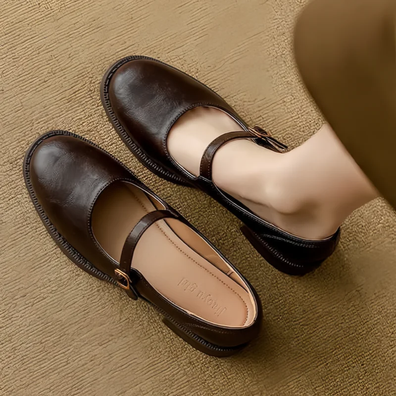 Brown Grace Classic Comfort Mary Janes by THE WHITMORE FAMILY, featuring a polished leather finish and a secure strap for casual wear.