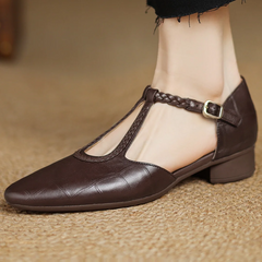Brown leather Lily Mary Janes by THE WHITMORE FAMILY featuring classic strap design and rounded toe on a neutral background.