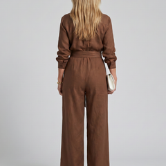 Brown Jovie long sleeve button-front wide-leg jumpsuit by THE WHITMORE FAMILY, displayed on a hanger