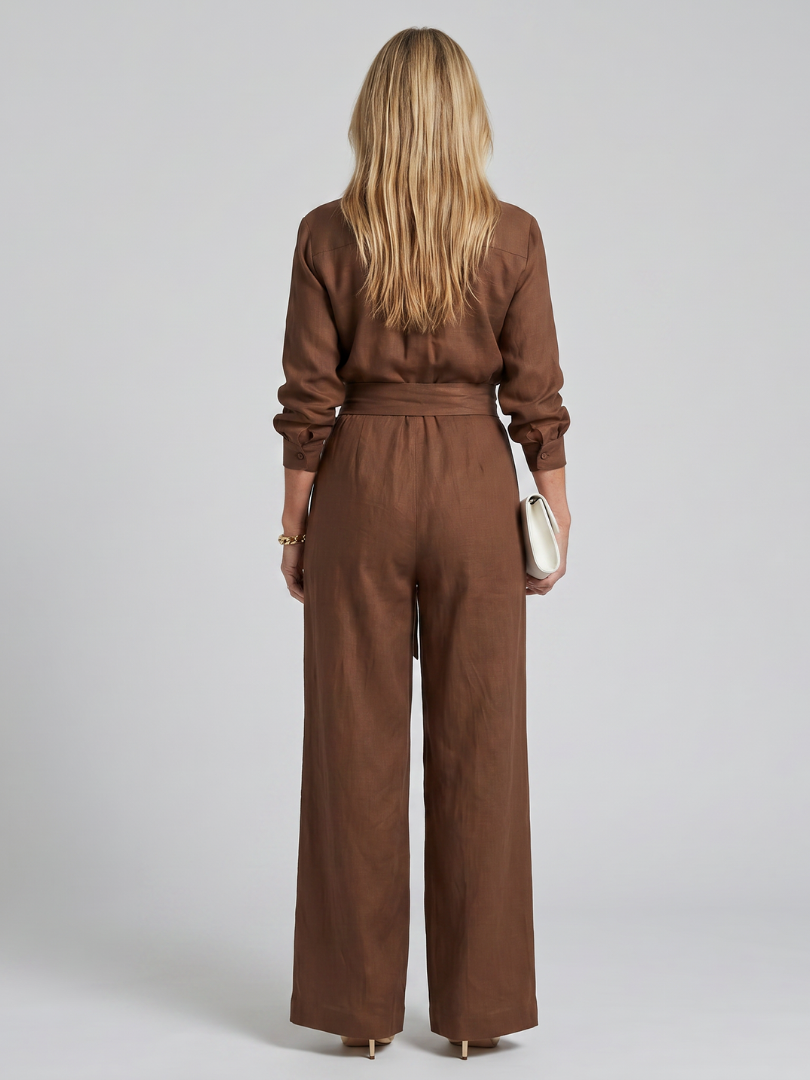 Brown Jovie long sleeve button-front wide-leg jumpsuit by THE WHITMORE FAMILY, displayed on a hanger