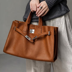 Brown leather tote bag from THE WHITMORE FAMILY's The Meridian collection, shown on a model with shoulder straps and spacious interior.