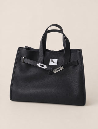Black leather tote bag with sleek design from THE WHITMORE FAMILY, featuring sturdy handles and spacious interior.