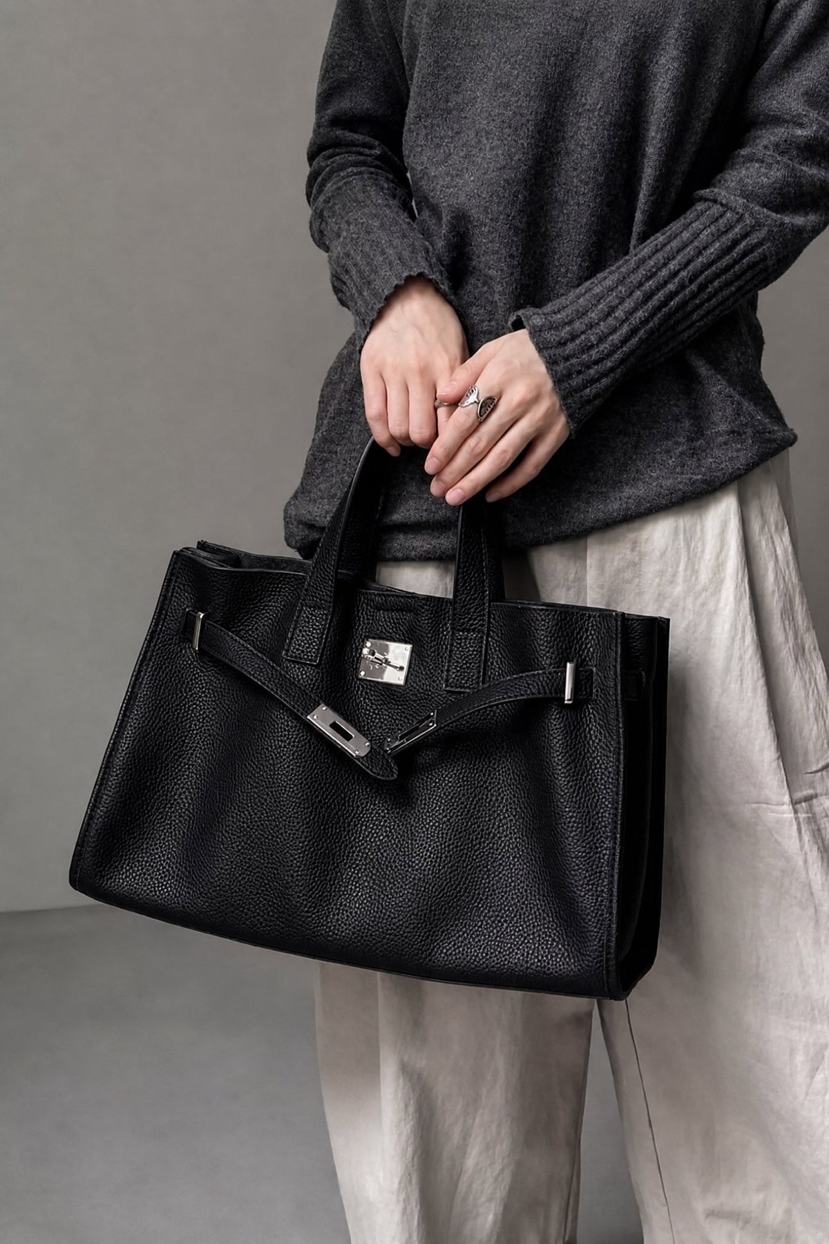Black leather tote bag from THE WHITMORE FAMILY's Meridian collection, shown on a model, showcasing stylish and spacious design.