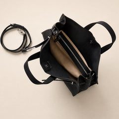 Black leather tote bag with spacious interior and multiple compartments from THE WHITMORE FAMILY's Meridian collection.