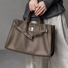 Coffee brown leather tote by THE WHITMORE FAMILY, model holding The Meridian Leather Tote showcasing its size and design features.