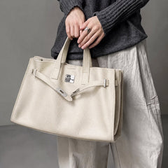 Cream leather tote bag by THE WHITMORE FAMILY, shown on model, with structured shape and elegant design.