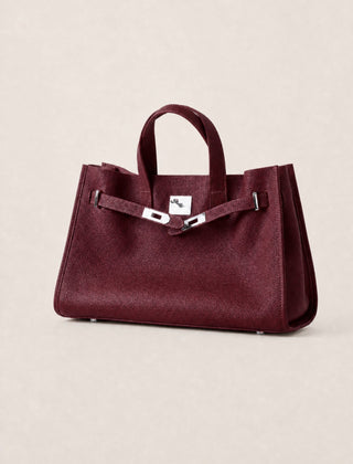 Maroon leather tote bag by THE WHITMORE FAMILY, featuring sturdy handles and sleek design, on a neutral background.