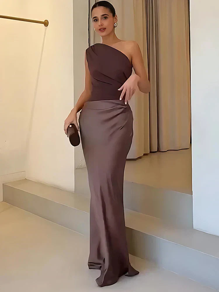 Ashley maxi dress by THE WHITMORE FAMILY in brown satin with a guilt detail, shown on a small-sized model.