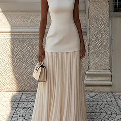 Cream Serena pleated maxi dress by THE WHITMORE FAMILY, flowing fabric, elegant design, and full-length silhouette.