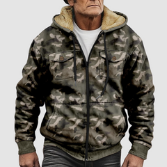 Sam™ camouflage jacket by THE WHITMORE FAMILY displayed on a hanger, featuring a green and brown woodland camo pattern.