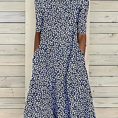 Blue Annie Coastal Bloom Dress by THE WHITMORE FAMILY, shown on a model with floral pattern and flowing fabric.