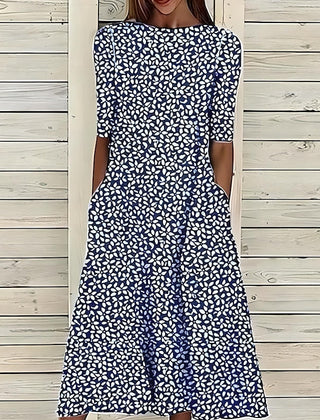 Blue Annie Coastal Bloom Dress by THE WHITMORE FAMILY, shown on a model with floral pattern and flowing fabric.