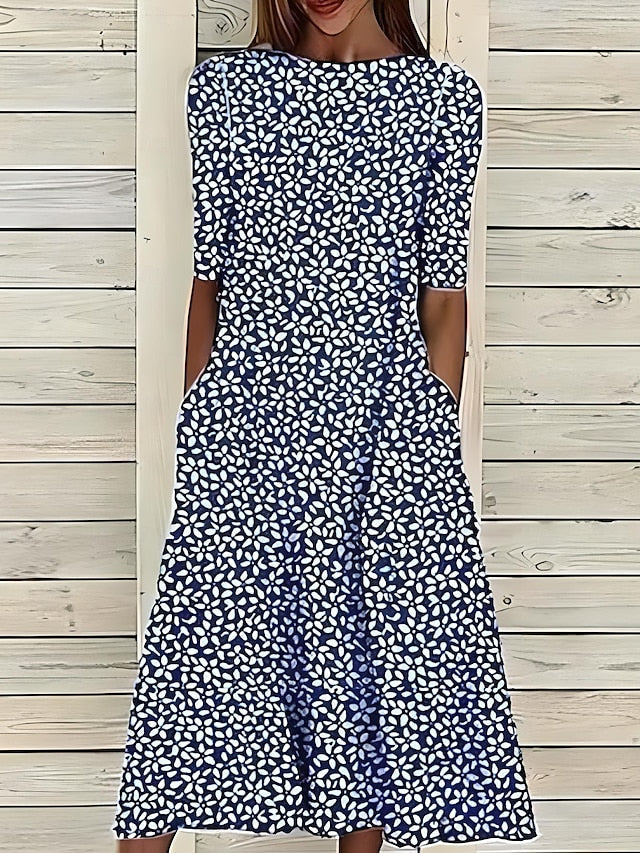 Blue Annie Coastal Bloom Dress by THE WHITMORE FAMILY, shown on a model with floral pattern and flowing fabric.