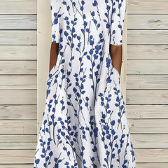 An Annie Coastal Bloom Dress by THE WHITMORE FAMILY featuring a blue floral pattern on lightweight fabric.
